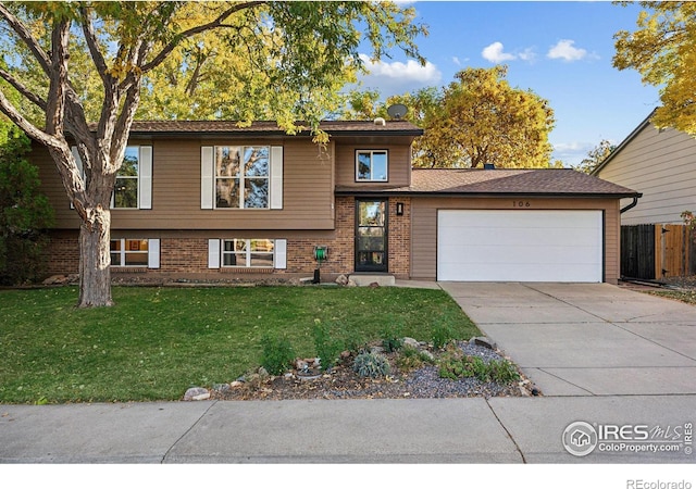 tri-level home with fence, a front lawn, brick siding, a garage, and concrete driveway