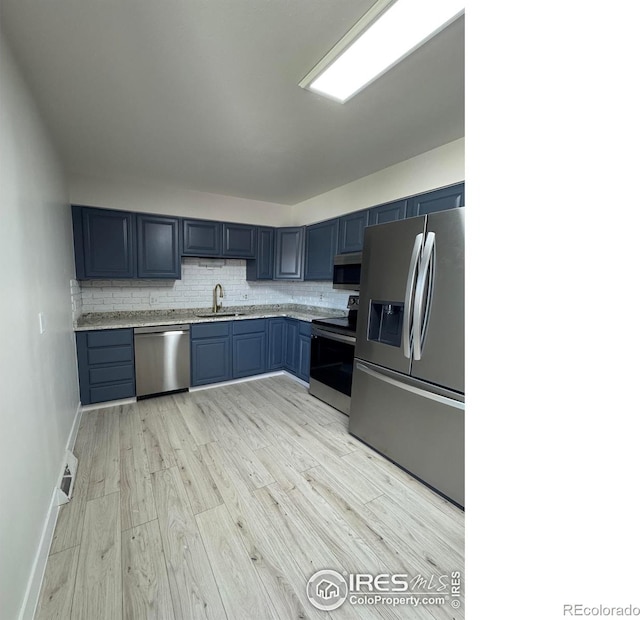 2221 E 84th Ave, Denver, CO 80229 - kitchen with stainless steel appliances, a sink, tasteful backsplash, light wood-style floors, and blue cabinetry