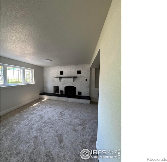2221 E 84th Ave, Denver, CO 80229 - unfurnished living room with a brick fireplace, carpet flooring, baseboards, and a textured ceiling
