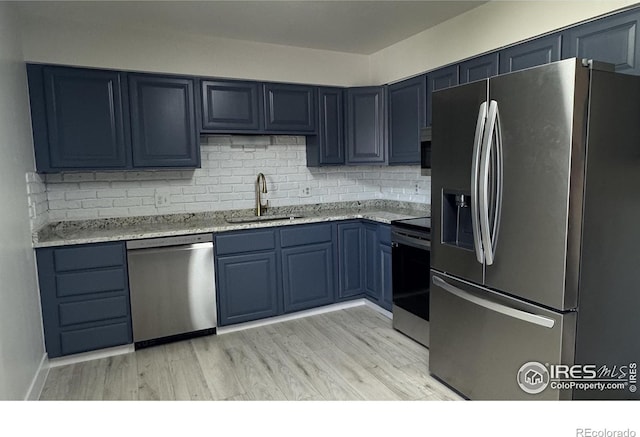 2221 E 84th Ave, Denver, CO 80229 - kitchen with appliances with stainless steel finishes, a sink, backsplash, light wood-style floors, and blue cabinetry