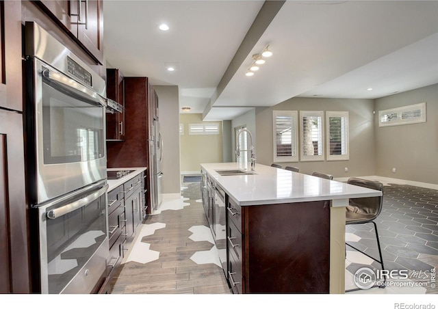 2624 S Race St, Denver, CO 80210 - kitchen featuring a sink, a kitchen bar, baseboards, a center island with sink, and double oven