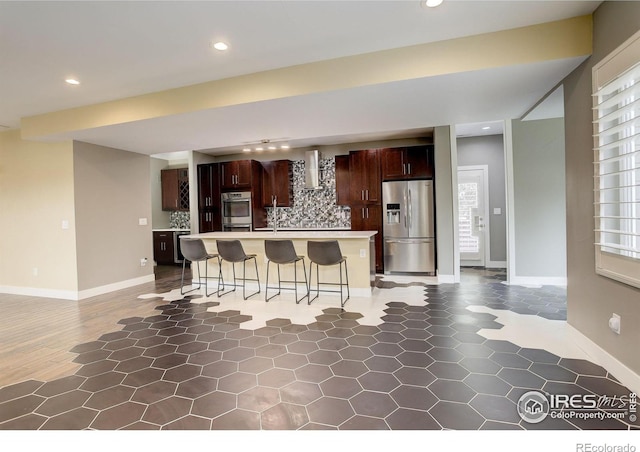 2624 S Race St, Denver, CO 80210 - kitchen with appliances with stainless steel finishes, wall chimney exhaust hood, backsplash, a kitchen breakfast bar, and light countertops
