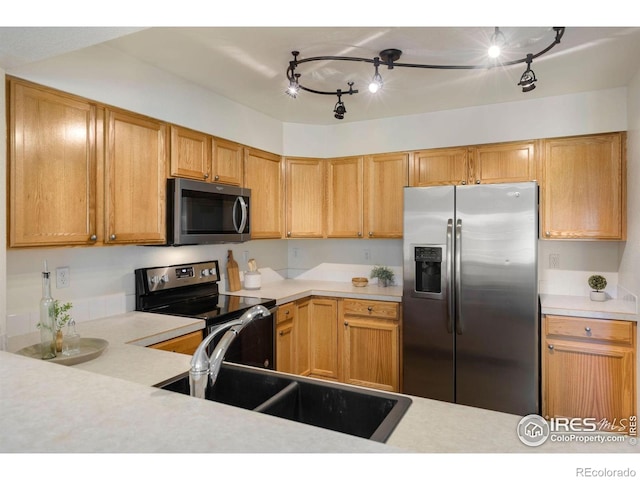 kitchen with track lighting, light countertops, a sink, and stainless steel appliances