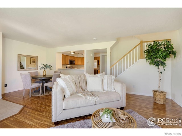living room with baseboards, stairs, and wood finished floors
