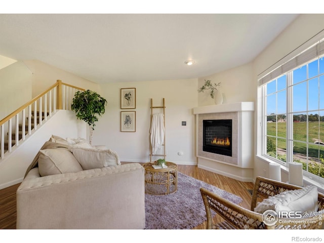 living room with baseboards, wood finished floors, stairway, and a tile fireplace