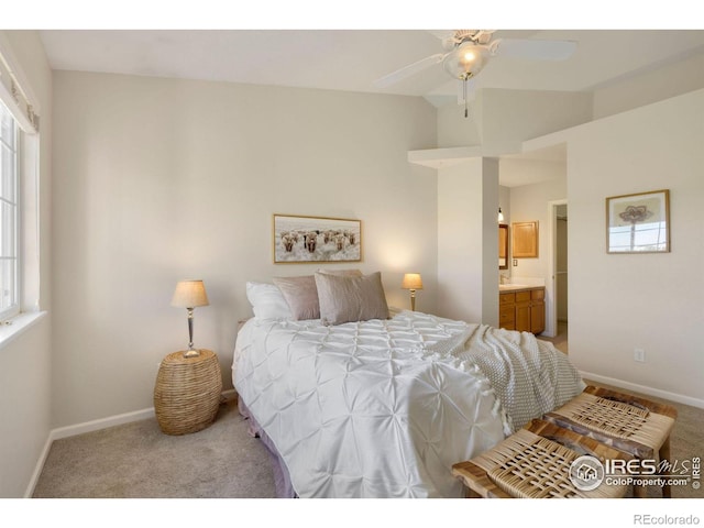 carpeted bedroom featuring baseboards, lofted ceiling, and ensuite bath