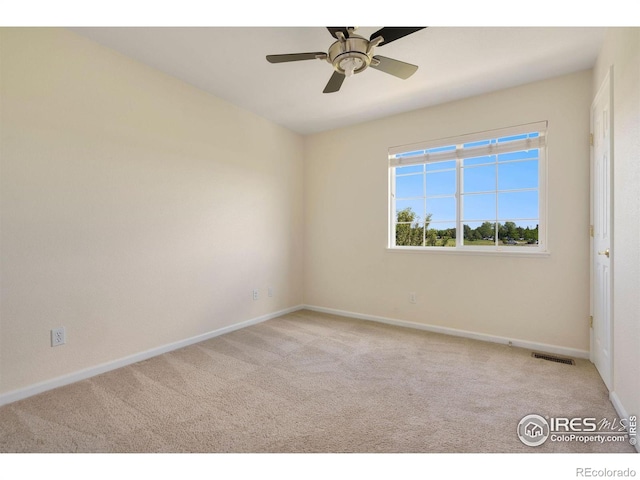 carpeted spare room with baseboards, a ceiling fan, and visible vents