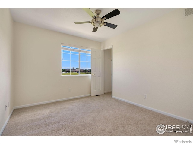 carpeted spare room featuring visible vents, a ceiling fan, and baseboards