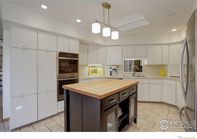 6611 Lakeview Dr, Boulder, CO 80303 - kitchen with a sink, wood counters, a center island, stainless steel appliances, and white cabinetry