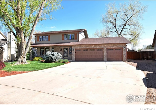 1021 Pinyon Dr, Windsor, CO 80550 - traditional home featuring brick siding, fence, a front lawn, concrete driveway, and an attached garage
