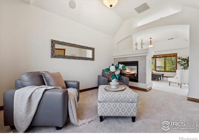 carpeted living area with baseboards, visible vents, lofted ceiling, and a tile fireplace