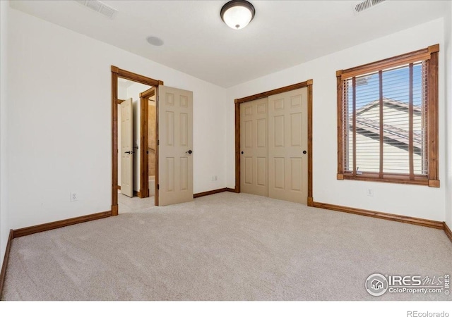 unfurnished bedroom with baseboards, visible vents, carpet, and a closet
