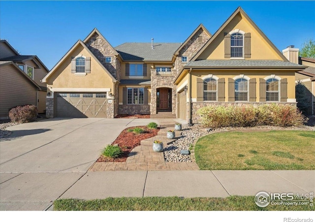 view of front facade with a garage, stucco siding, concrete driveway, and stone siding