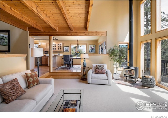 187 Rocky Knob Ln, Nederland, CO 80466 - living room with carpet floors, a wood stove, beam ceiling, wood ceiling, and a chandelier