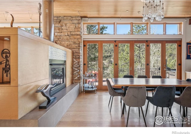 1127 Valley Ln, Boulder, CO 80302 - dining area featuring french doors, wood finished floors, wooden ceiling, a glass covered fireplace, and an inviting chandelier