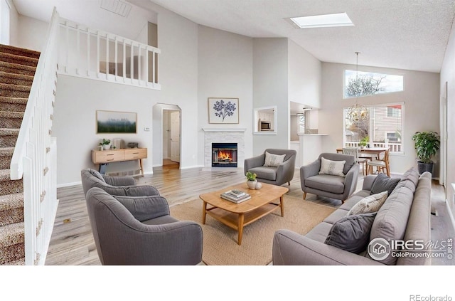2330 Redwood Ave, Lafayette, CO 80026 - living room featuring wood finished floors, high vaulted ceiling, a notable chandelier, a glass covered fireplace, and stairs