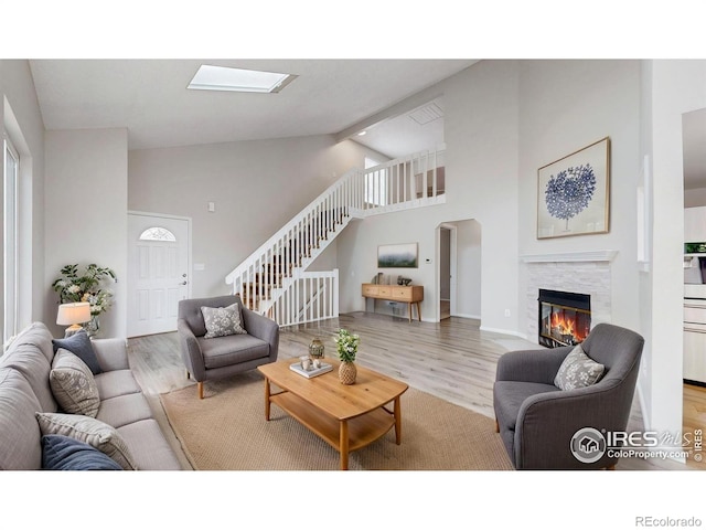 living room featuring stairway, high vaulted ceiling, a fireplace, and wood finished floors