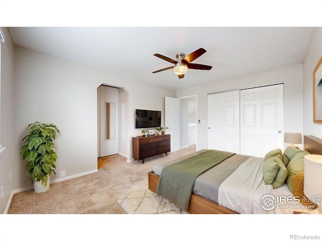 bedroom featuring carpet floors, arched walkways, a ceiling fan, baseboards, and a closet