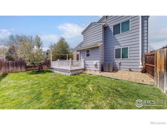 rear view of property featuring a fenced backyard, central air condition unit, a yard, and a deck