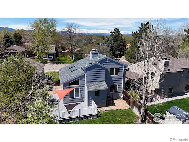 exterior space featuring a deck, a shingled roof, a chimney, and a fenced backyard