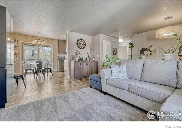 150 Lori Dr, Loveland, CO 80537 - living room featuring attic access, a textured ceiling, wood finished floors, baseboards, and a notable chandelier