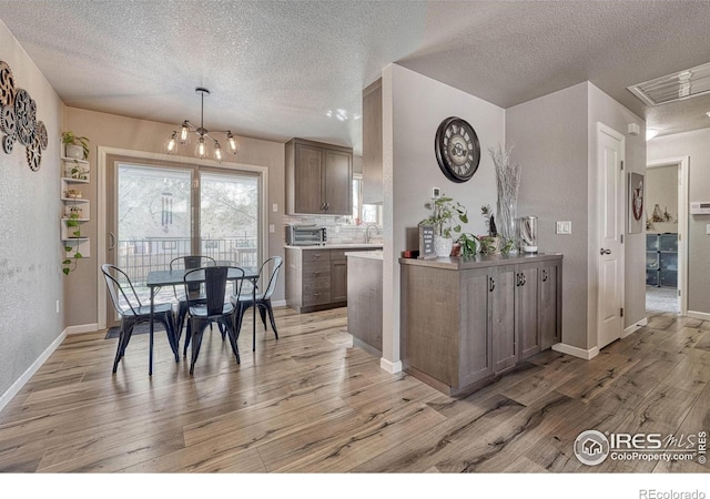 150 Lori Dr, Loveland, CO 80537 - kitchen with a toaster, light wood-style flooring, a textured ceiling, and a chandelier