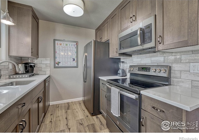 150 Lori Dr, Loveland, CO 80537 - kitchen featuring appliances with stainless steel finishes, a sink, light wood finished floors, baseboards, and backsplash