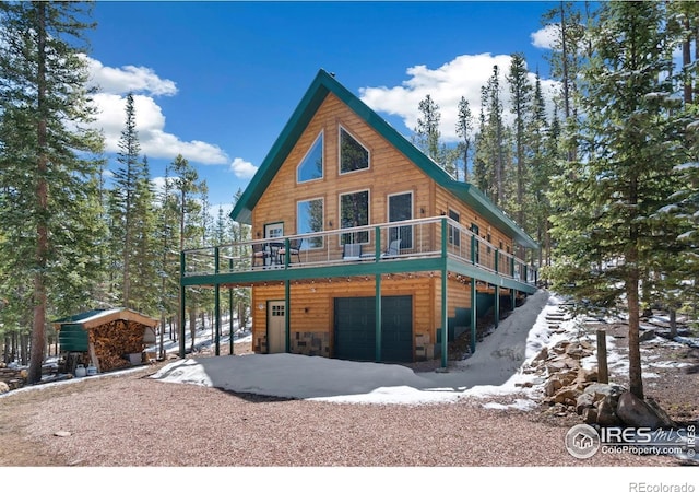 2356 Ottawa Way, Red Feather Lakes, CO 80545 - view of front facade featuring faux log siding, an attached garage, central AC, a wooden deck, and a storage unit