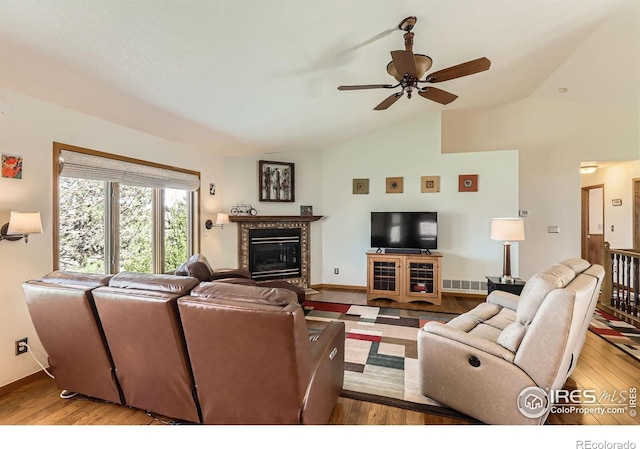 living room featuring wood finished floors, baseboards, ceiling fan, lofted ceiling, and a high end fireplace