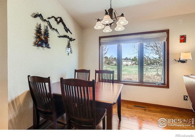 dining space featuring a chandelier, baseboards, visible vents, and wood-type flooring