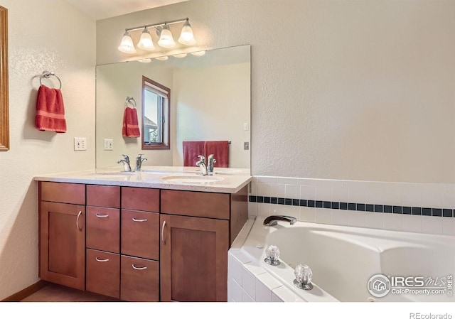 bathroom featuring a sink, double vanity, a textured wall, and a garden tub
