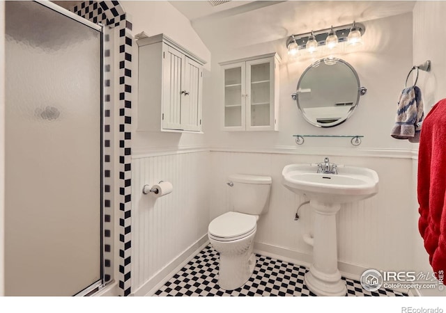 bathroom with tile patterned floors, a wainscoted wall, toilet, and a shower stall