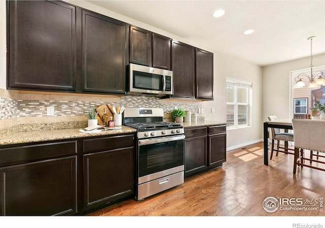 1693 Maseca Plaza Way, Severance, CO 80550 - kitchen with stainless steel appliances, decorative backsplash, hanging light fixtures, a chandelier, and baseboards