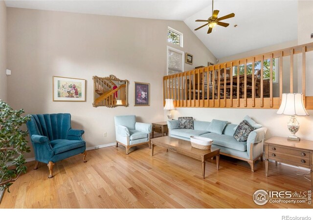 living room featuring baseboards, a ceiling fan, high vaulted ceiling, and wood finished floors
