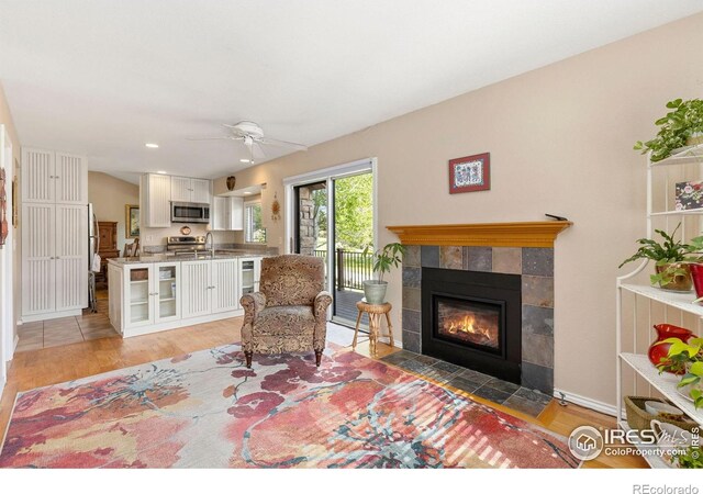 living area featuring a fireplace, baseboards, light wood-type flooring, recessed lighting, and a ceiling fan