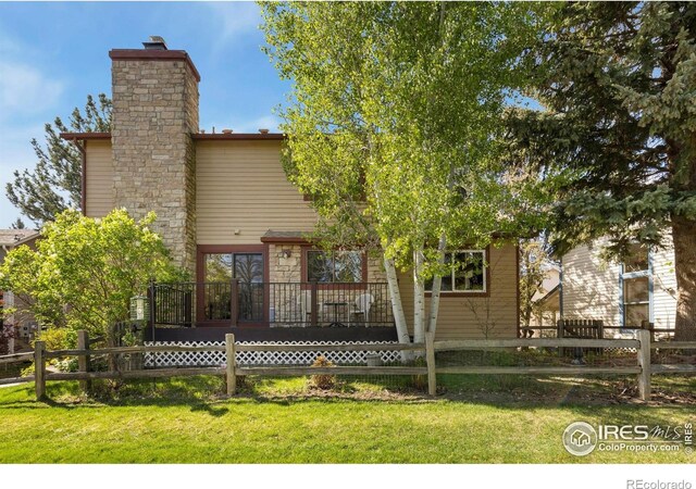 rear view of property featuring a lawn, fence, and a chimney