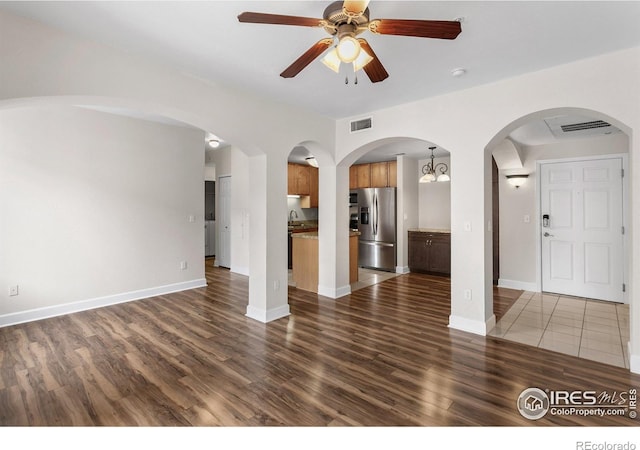 unfurnished living room with visible vents, a ceiling fan, baseboards, dark wood-type flooring, and a sink