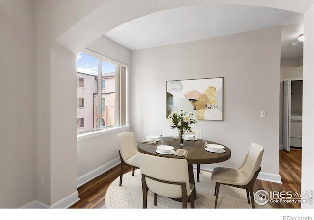 dining space with baseboards, arched walkways, and wood finished floors