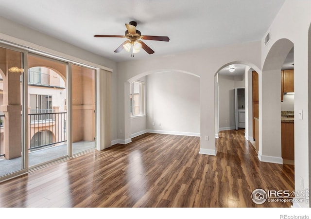 unfurnished room with visible vents, arched walkways, dark wood-style flooring, and ceiling fan