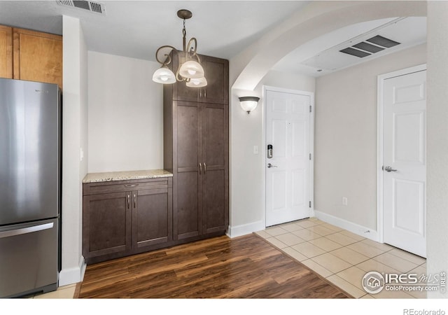 interior space featuring freestanding refrigerator, arched walkways, visible vents, and wood finished floors