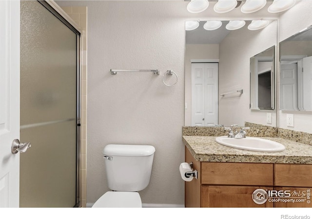 bathroom with vanity, a shower with door, and toilet