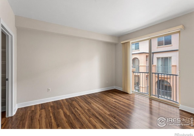 spare room featuring baseboards and wood finished floors