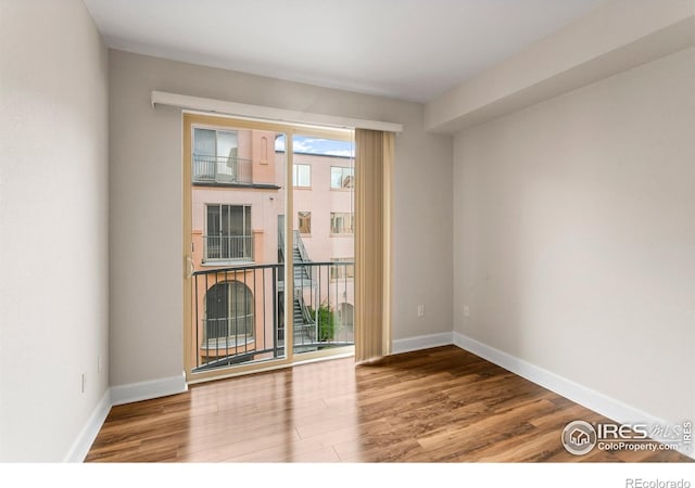 spare room with baseboards and wood finished floors