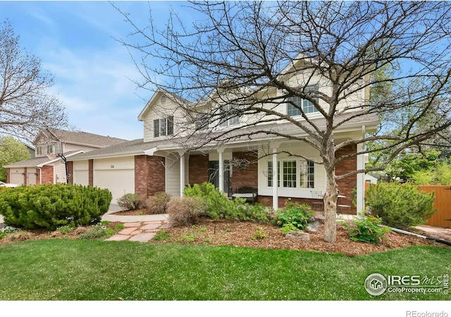 traditional home featuring a garage, fence, covered porch, a front yard, and brick siding