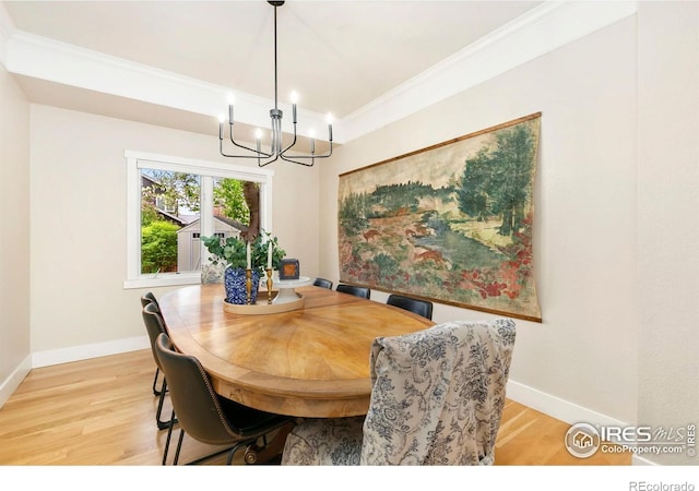 dining space with crown molding, baseboards, an inviting chandelier, and light wood-style flooring