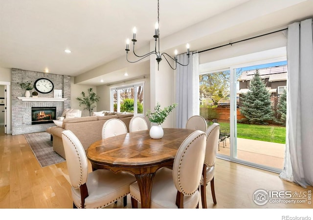 dining room with a brick fireplace, recessed lighting, a chandelier, and light wood-style floors