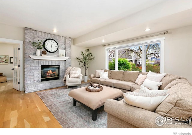 living area featuring a brick fireplace, recessed lighting, and wood finished floors