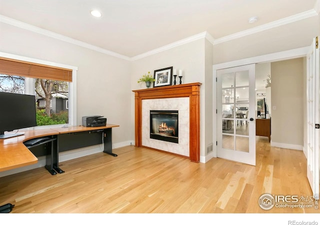 living room with baseboards, a tile fireplace, ornamental molding, and light wood-type flooring