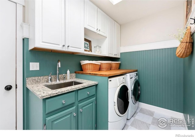 washroom featuring cabinet space, a sink, baseboards, light floors, and separate washer and dryer