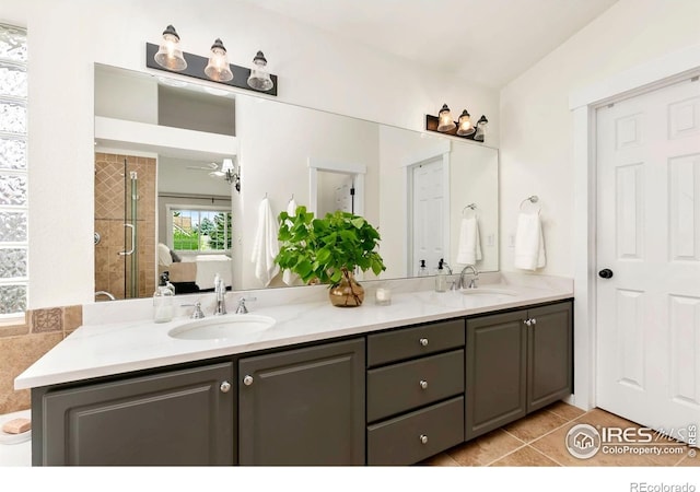 full bathroom with double vanity, a tile shower, a sink, and tile patterned flooring